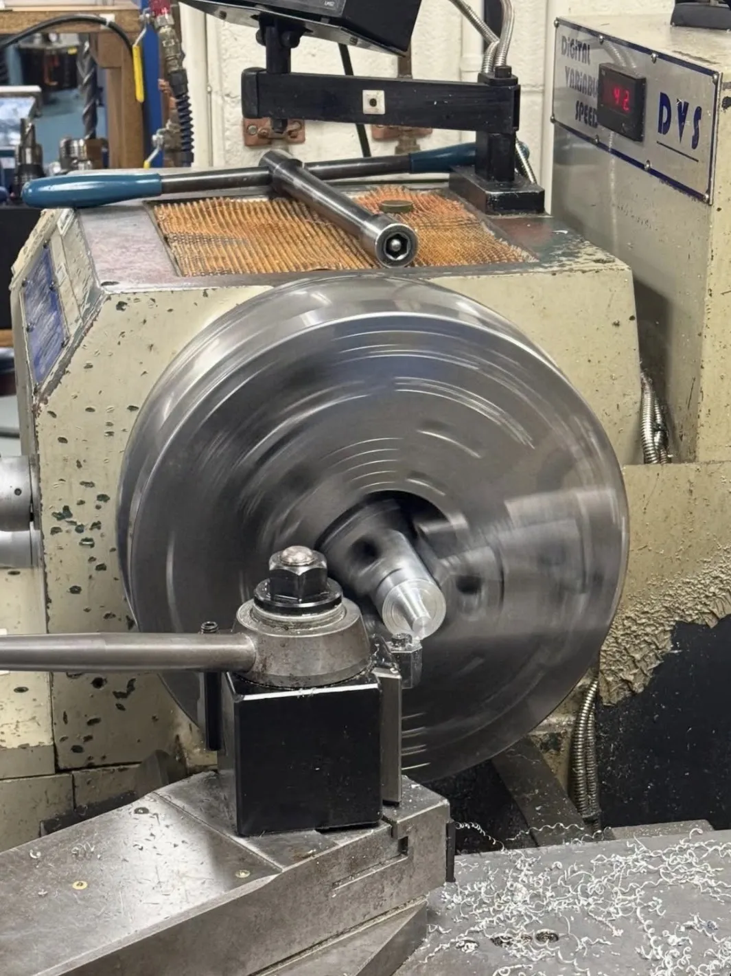 An aluminum part being turned on a manual lathe