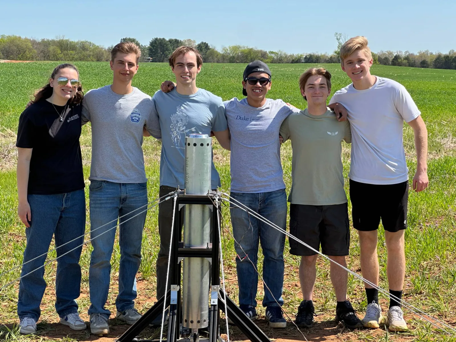 Duke AERO team members in a field with the static fire test stand