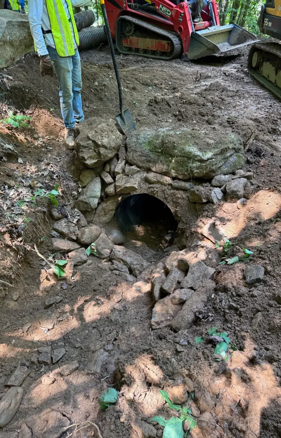 A newly placed culvert pipe set into muddy ground